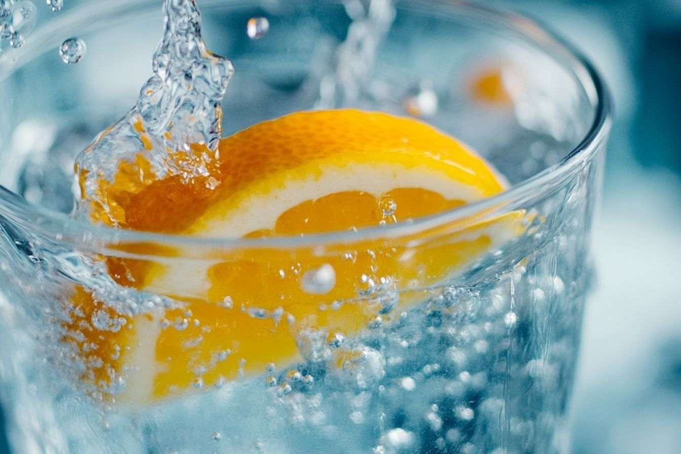 Image d'illustration. Gros plan d un verre rafraîchissant rempli d eau claire et d une touche de jus de fruit